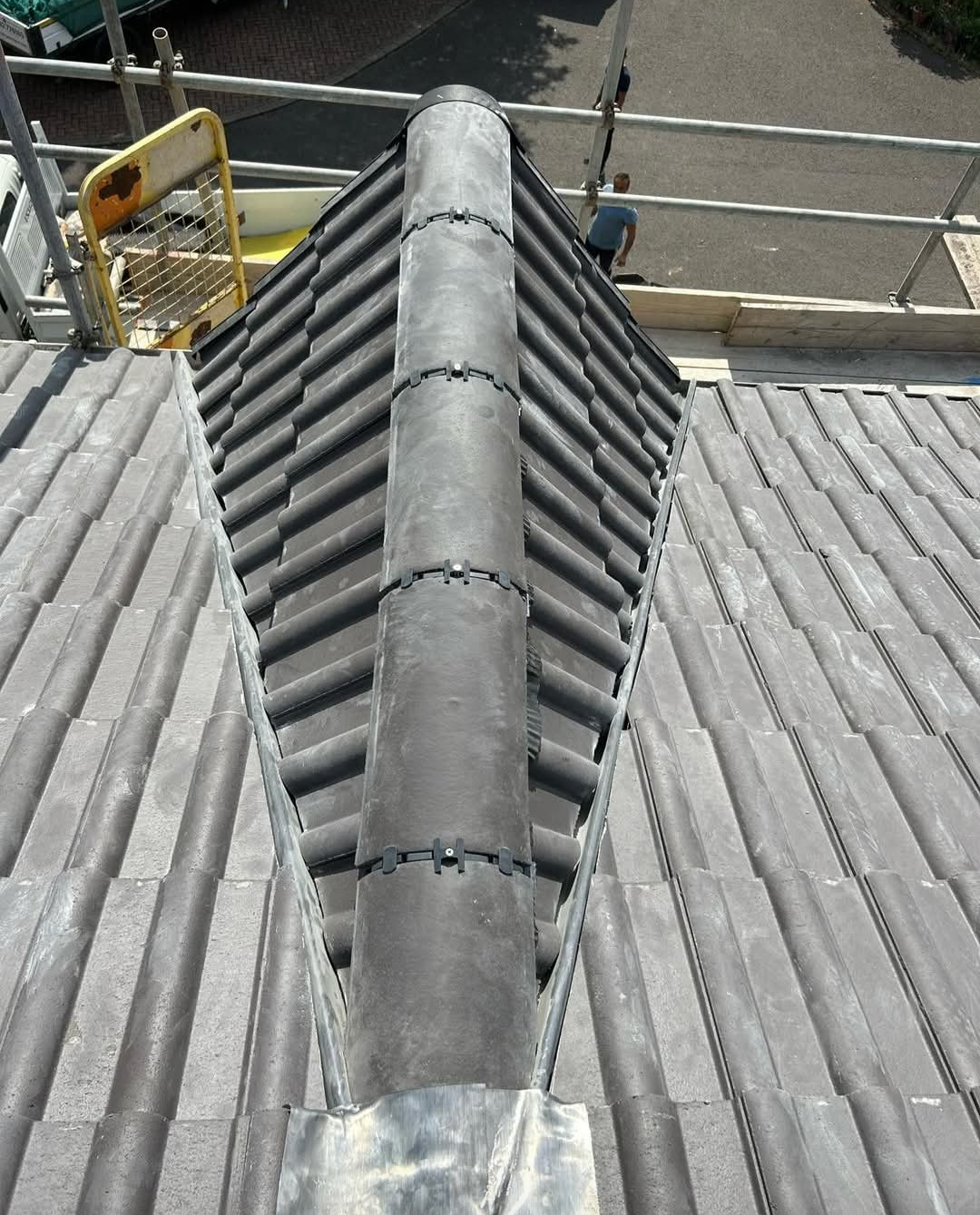 Close detail of newly fitted grey ridge tiles and dry ridge fixings on a tiled roof
